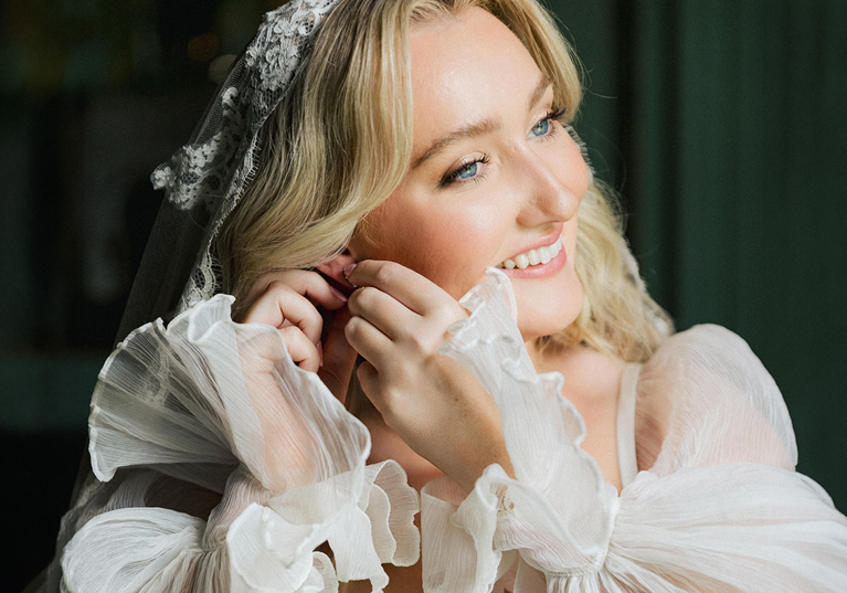 Bride smiling while getting ready, wearing natural glowing wedding makeup by Gosia May MUA.